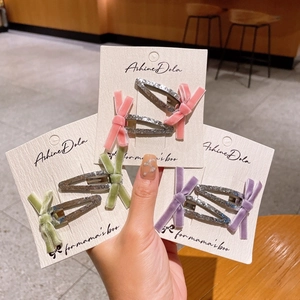 Détail de barrettes à nœuds en velours rose et violet avec une base pailletée brillante