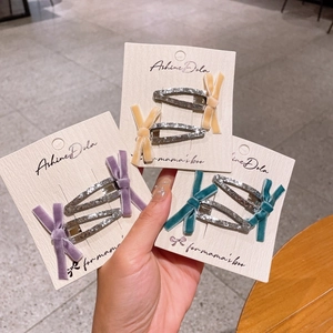 Détail de barrettes à nœuds en velours avec base triangulaire pailletée en trois couleurs