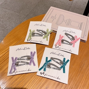 Lot de barrettes argentées avec nœuds en velours colorés sur carte de présentation