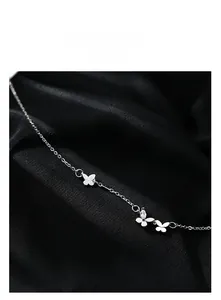 Gros plan du bracelet papillon argenté avec zircons brillants sur soie noire lisse