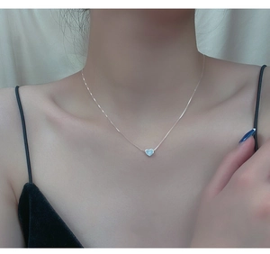 Detail of silver heart pendant necklace on collarbone with white mother of pearl inlay