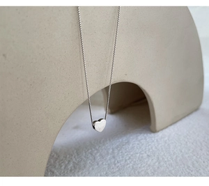 Detailed close-up of a silver minimalist heart pendant on a delicate box chain