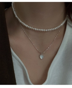 Dettaglio collana s925 in argento a strati con pendente a cuore e choker di perle su modella