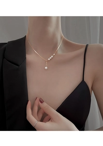 Close-up of elegant gold chain necklace with five white pearls worn on a model's neck