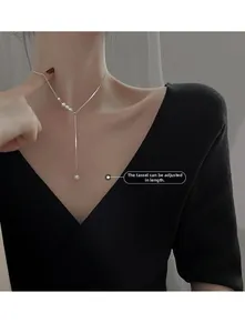 Close-up of adjustable silver Y-necklace with pearls on model, featuring tassel design