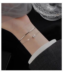 Close-up of elegant S925 sterling silver layered bracelet on wrist with silk background