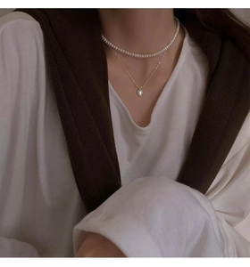 Dettaglio della collana con ciondolo a cuore in argento S925 e girocollo di perle bianche