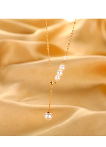 Detailed close-up of 18k gold-plated pearl lariat necklace on silk fabric backdrop