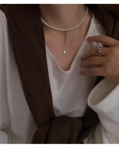 Primo piano della collana a doppio strato in argento S925 con cuore e perle su modella