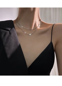 Detail of elegant butterfly pendant on double-layer silver chain worn by a female model