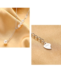 Detail of S925 sterling silver heart tag and lustrous white pearls on Y-shaped necklace