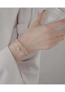 Close-up of minimalist S925 silver double-layered bracelet on female wrist with glass