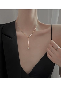 Detail of a gold Y-shaped pearl necklace with graduated pearls on a model in a black blazer