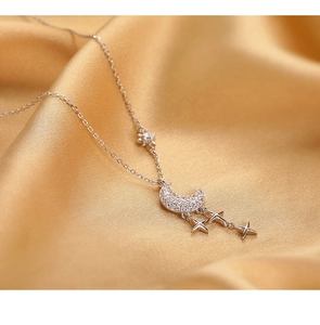 Détail du pendentif lune et étoile en argent avec cristaux sur un tissu en satin
