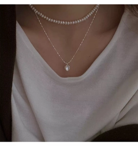 Primo piano della collana con cuore in argento S925 e girocollo di perle su modella