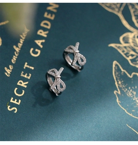 Detailed close-up of bow-knot hoop earrings with sparkling cubic zirconia on a gift box