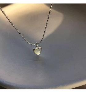 Vista macro di una collana a cuore in argento S925 con intarsio in madreperla e catena sfaccettata