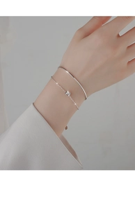 Close-up of minimalist silver double-layer bracelet and bangle set with cylinder charm