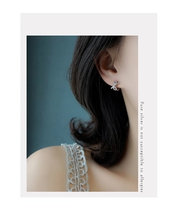 Close-up of elegant silver bow earrings with pave crystals worn by a model