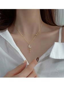 Gros plan d'un collier en argent S925 doré avec pendentif lune et étoiles en diamants
