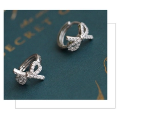Macro detail of bow-shaped silver hoop earrings with shimmering cubic zirconia settings
