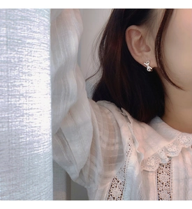Close-up of elegant silver bow earrings with sparkling pavé crystals on a female model