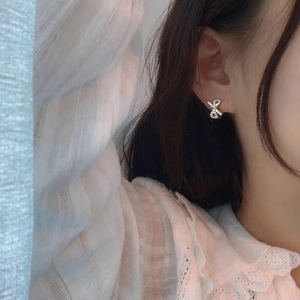 Close-up of a bow-knot stud earring with sparkling zircons worn by a model
