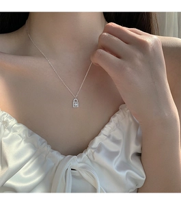 Close-up of a silver lock necklace with sparkling zircon on a woman's collarbone