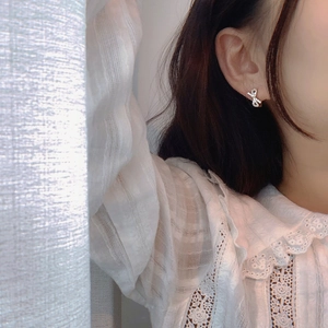 Elegant silver bow earrings with sparkling zircons worn by a model in warm white light