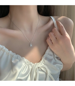 Close-up of sparkling silver padlock necklace pendant worn by a model on white satin