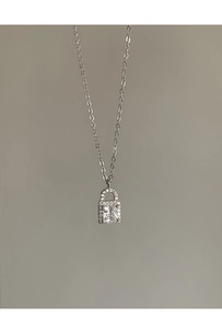 Macro detail of silver padlock pendant featuring a large square zircon and fine pavé stones