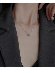Détail d'un collier en argent S925 porté par un mannequin en blazer gris chic