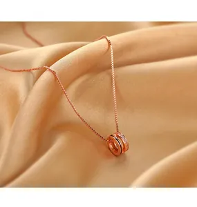 Détail macro du collier en or rose avec anneaux entrelacés et pierres de zircone cubique