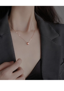 Gros plan du collier double anneau en or rose serti de zircons porté par un mannequin femme