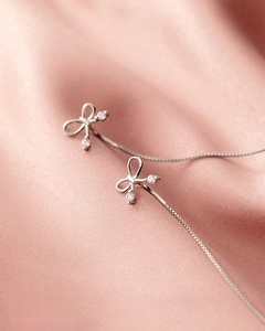 Détail de boucles d'oreilles nœud en argent S925 avec strass brillants et chaîne vénitienne