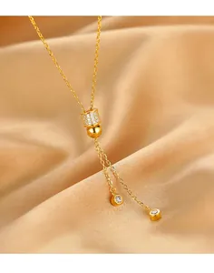 Détail d'un collier en argent s925 doré avec pendentif cylindrique et élégants glands