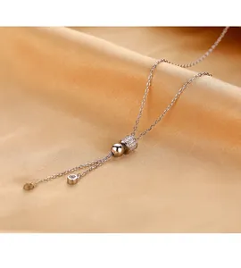 Gros plan d'un collier en Y or rose avec cylindre en cristal et glands sur du satin