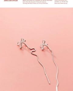 Détail de boucles d'oreilles nœud en argent avec zircons et longue chaîne à mailles