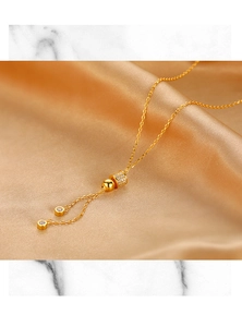 Détail macro du collier à pompon doré s925 avec pavé de zircon sur de la soie