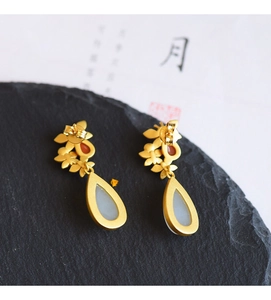 Detail of ethnic style gold drop earrings with white jade stone and flower petals