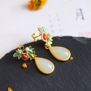 Detailed macro view of ethnic silver teardrop earrings with jade and butterfly motifs