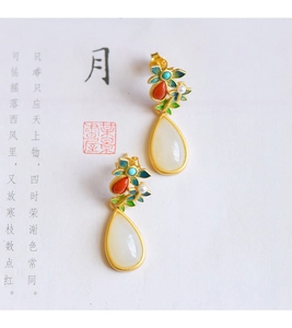 Close-up of ethnic silver earrings with white jade drops and colorful floral details