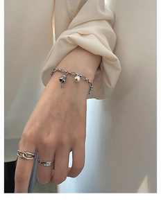 Detail of silver lucky cat bell bracelet and vintage rings worn on hand for women