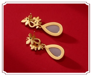 Detailed macro of gold butterfly flower earrings with purple teardrop gemstones