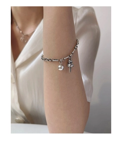 Detailed close-up of a silver beaded bracelet with bell and mushroom charms on a model