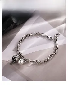Detailed macro view of vintage silver bell and spherical charms on oval link chain bracelet