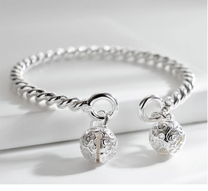 Macro shot of silver twisted bangle detailing hollow-out floral engraved bells charms