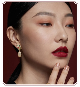 Close-up of ethnic style teardrop earrings with gold flowers and white jade stone