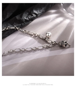 Macro shot of a silver Lucky Cat bell pendant with Pingan engraving on a chain