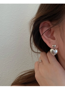 Gros plan d'élégantes boucles d'oreilles cœur en argent S925 et bague ajourée